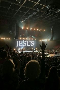 a large crowd at a concert with their hands up in the air and jesus sign above them