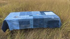 a blue table cloth sitting on top of a grass covered field in the middle of nowhere