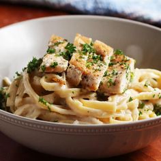 a close up of a bowl of pasta with meat and parmesan cheese on top