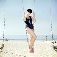 a woman in a bathing suit on a swing at the beach