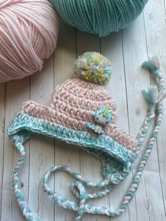 two balls of yarn and a crocheted hat