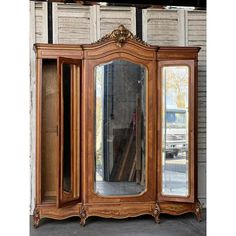 an antique looking wooden armoire with mirrors