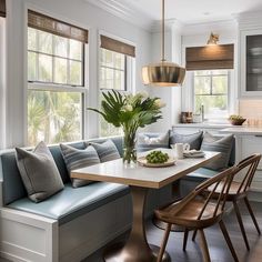 a kitchen with a table, couches and chairs in front of two windows next to a potted plant