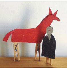 a wooden horse with a man standing next to it on top of a wood table