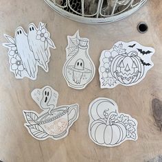 halloween stickers sitting on top of a wooden table next to a basket filled with pumpkins