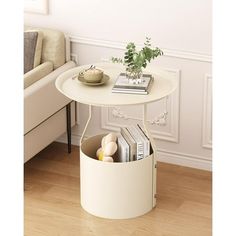 a white table with a magazine rack underneath it and a potted plant on top