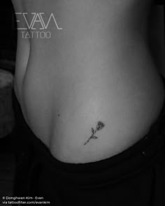 a woman's stomach with a small rose tattoo on her left side ribcage