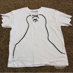 a white t - shirt with black stringing on the front and back, sitting on carpet