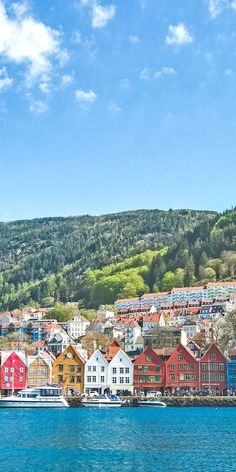 the water is blue and clear with many houses on it's sides, along with mountains in the background