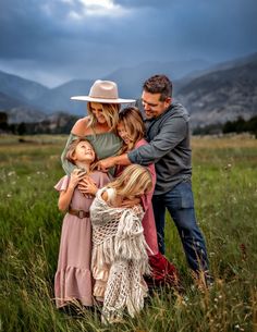 a family is posing for a photo in a field with mountains in the back ground