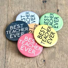 six badges with the words best teacher ever on them sitting on a wooden table top