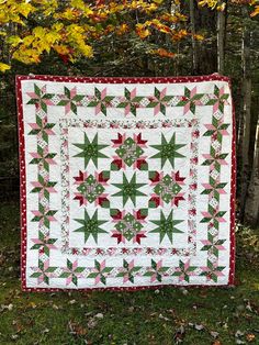 a quilted christmas tree skirt sitting on top of a grass covered field next to trees