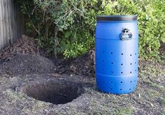 a blue trash can sitting in the dirt