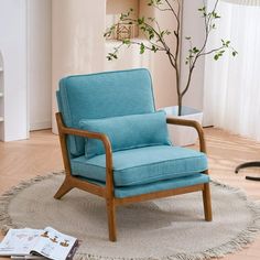 a blue chair sitting on top of a rug in front of a tree and window