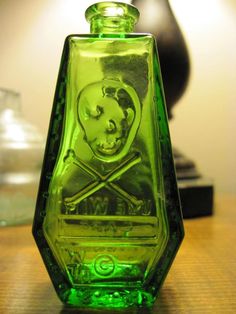 a green glass bottle with a skull and crossed bones in the center on a table