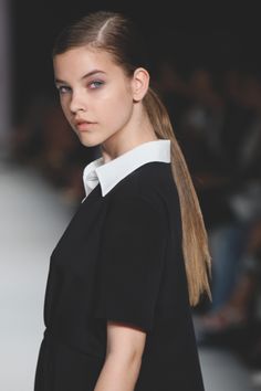 a woman with long hair standing on a runway