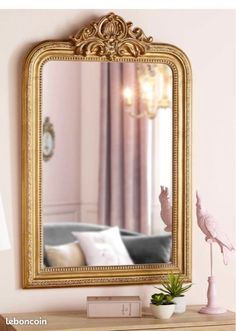 a mirror sitting on top of a wooden table next to a lamp and a vase