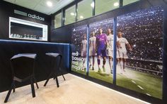 an indoor bar with chairs and a large poster on the wall behind it that says adidas