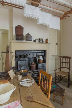 an old fashioned kitchen with a fireplace and wooden dining room table set for four people