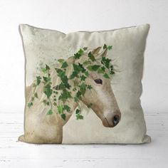 a white horse with green leaves on it's head is sitting on a pillow