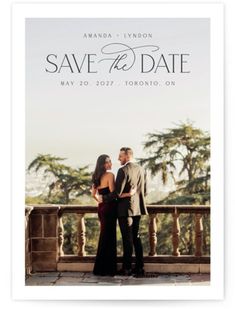 an elegant save the date photo card with a couple standing on a balcony in front of palm trees