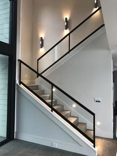 an empty room with some stairs and lights on the wall next to it's glass door