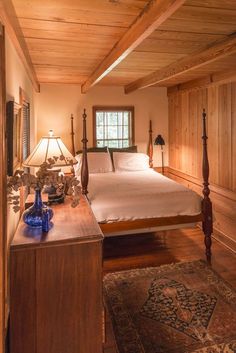 a bed sitting in a bedroom next to a wooden dresser and lamp on top of a hard wood floor