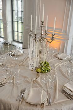 the table is set with white plates and silverware, candles, and napkins