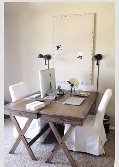 a desk with two computers on it and a white chair in front of the table