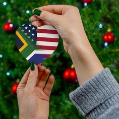 a person holding an ornament in front of a christmas tree