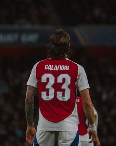 a soccer player with his back to the camera, wearing a red and white uniform