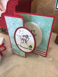 a card with a snowman on it sitting next to a red chair and christmas decorations