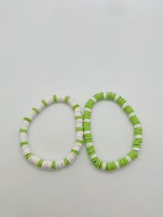 two green and white bracelets sitting next to each other