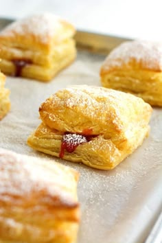 several pastries on a baking sheet covered in powdered sugar and jelly fillings