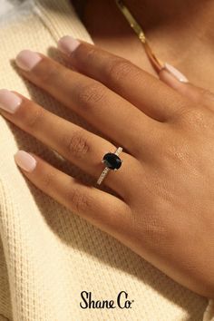 a woman's hand with a black diamond ring on her left hand and the words shine co written below it