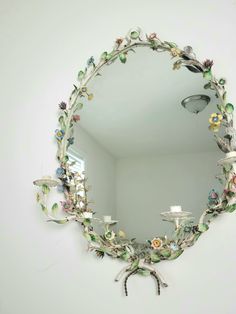 a mirror that is hanging on the wall with flowers and birds around it in a room