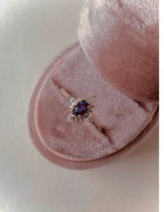 an engagement ring sits on top of a pink velvet box with a diamond in the center