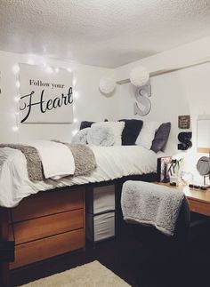 a bed room with a neatly made bed next to a desk and mirror on the wall