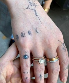 two people with tattoos on their hands holding each other's fingers and showing off their rings