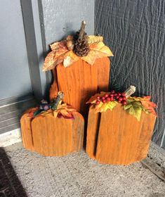 three wooden pumpkins with leaves and berries on them sitting in front of a door