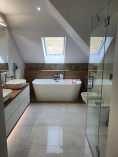 a bathroom with a large white bath tub sitting next to a walk in shower under a skylight