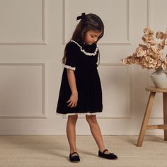 Our 'Amelia' Dress has a sweet collar along the neck that is framed by sweet bubbled sleeves and scalloped detailing along the bottom of the dress. Button closure down the back of the dress.*Baby sizes and 2y includes a coordinating bloomer.Featured in our 'black' hue.Care: Machine wash cold. Hang to Dry. Minor shrinkage may occur if tumble dried.Shell made of 77% Viscose, 23% Nylon, Lining made of 100% Viscose Made in China. Elegant Kids Outfit, Black Dress Kids, Black Toddler Dress, Black Baby Dress, Kids Black Dress, Velvet Black Dress, Back To School Clothes, Child Dress, Kid Outfits