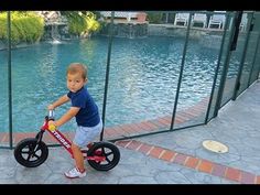 a young boy riding a bike next to a pool