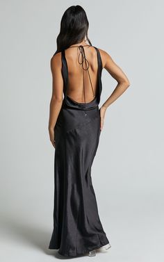 the back of a woman wearing a long black dress with spaghetti straps and an open back