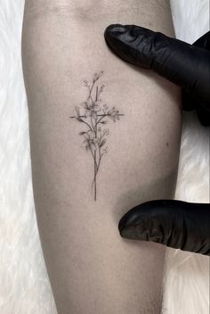 a person with a tattoo on their leg holding a flower in one hand and a black glove next to it