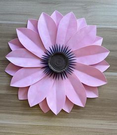 a pink paper flower sitting on top of a wooden table