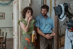 a man and woman standing next to each other in front of a camera set up