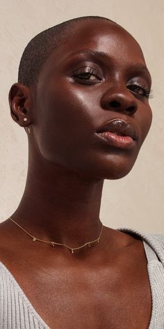 a woman with short hair wearing a choker and gold necklace on her neck, looking off to the side