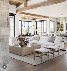 a living room filled with white furniture and lots of wood flooring next to large windows