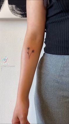 a woman with a small flower tattoo on her arm